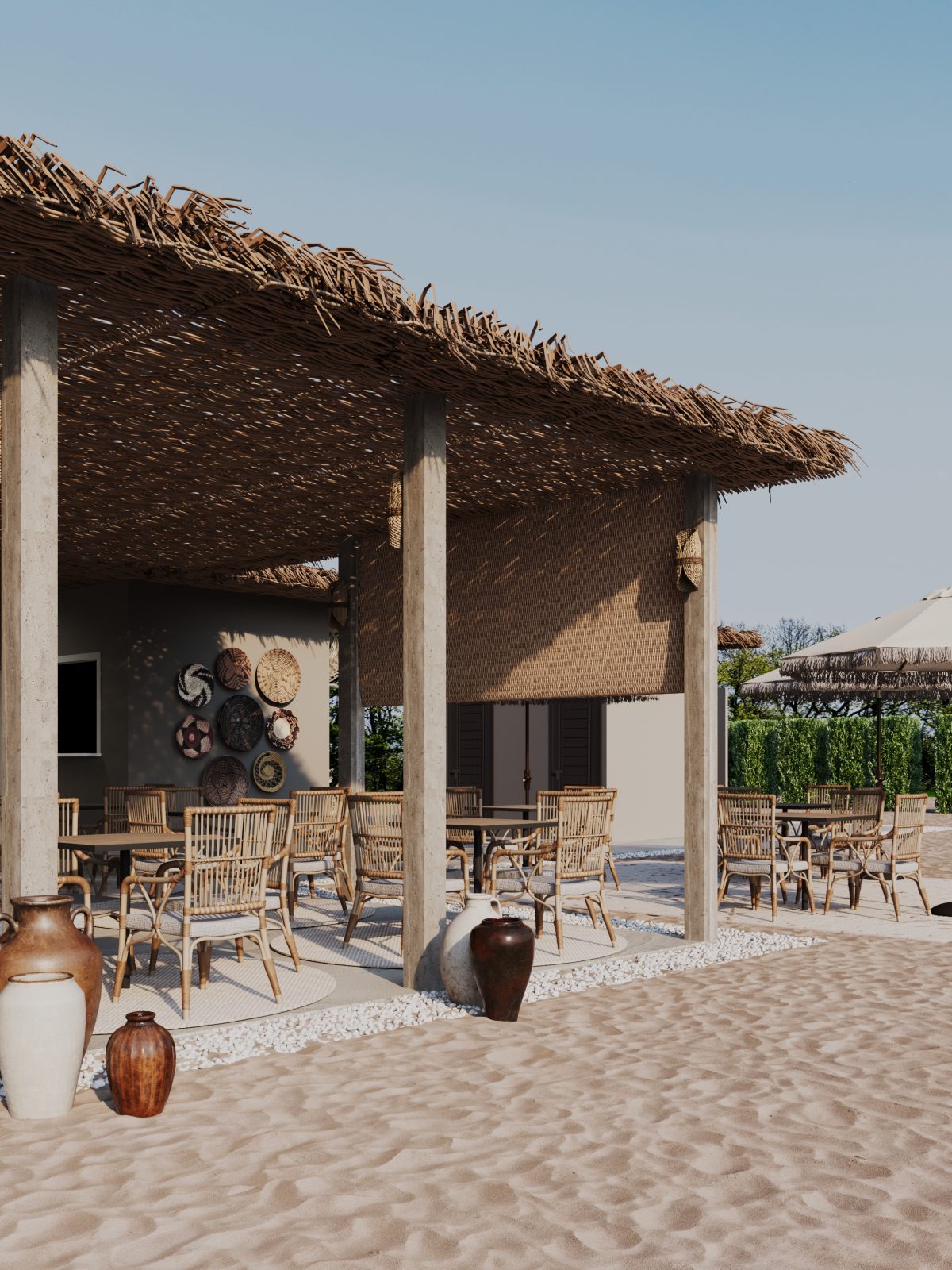 Outdoor beach lounge with wicker chairs, thatched roof, and decorative pottery on sandy ground.