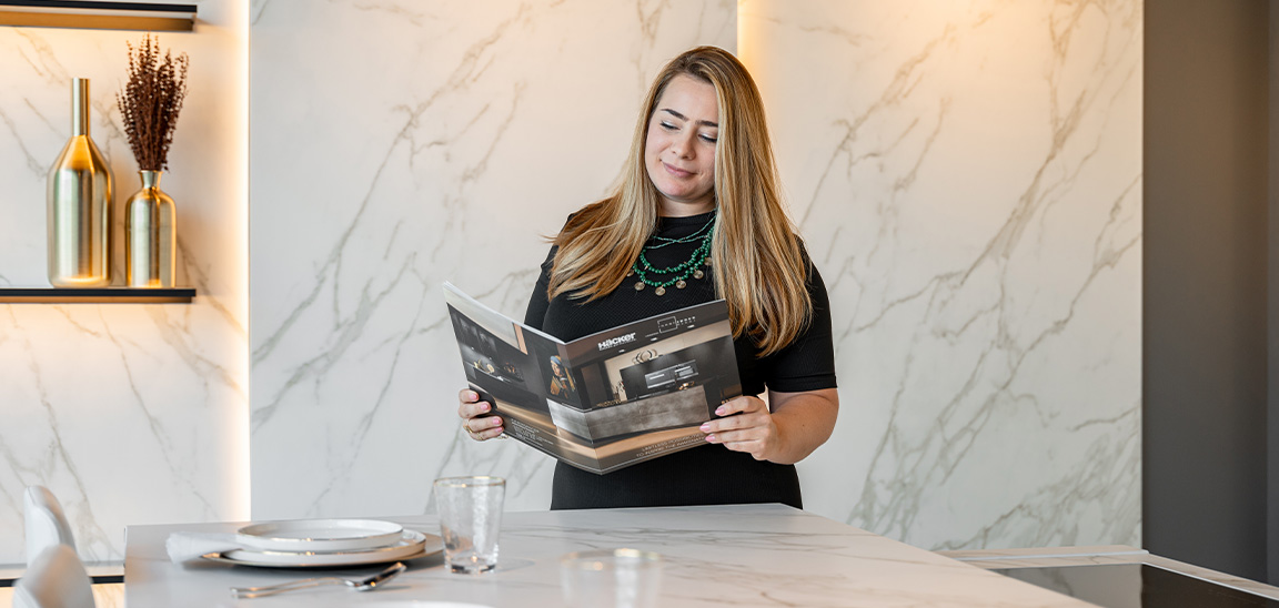 Woman reading a brochure in a modern kitchen with marble walls. Elementa Interior Design Dubai