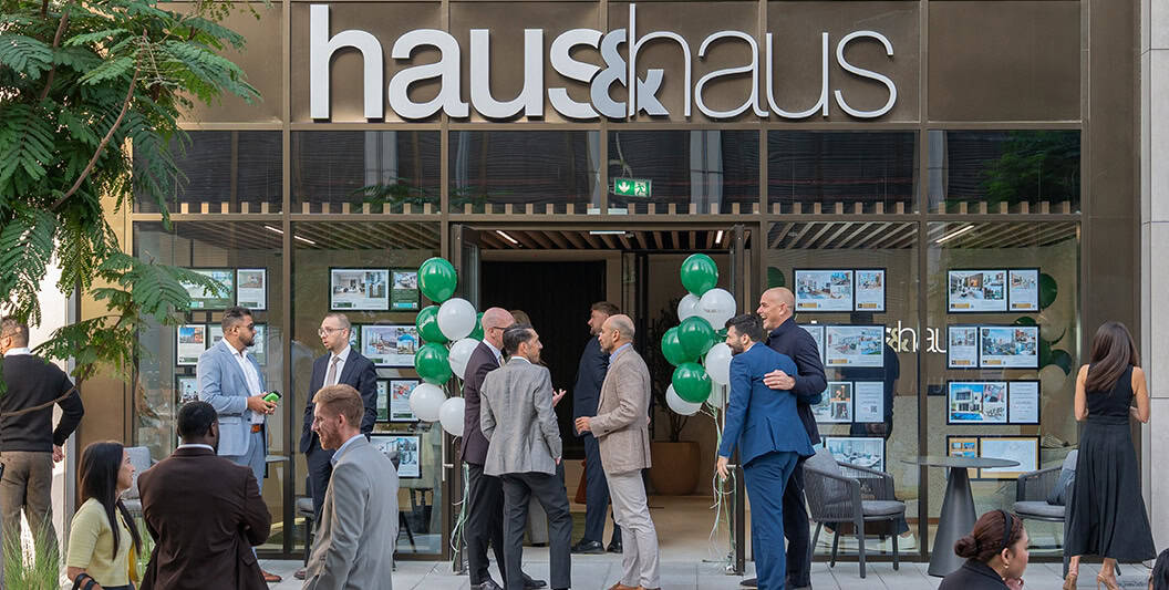 Modern building entrance with "haus & haus" signage and a crowd of people attending an event.