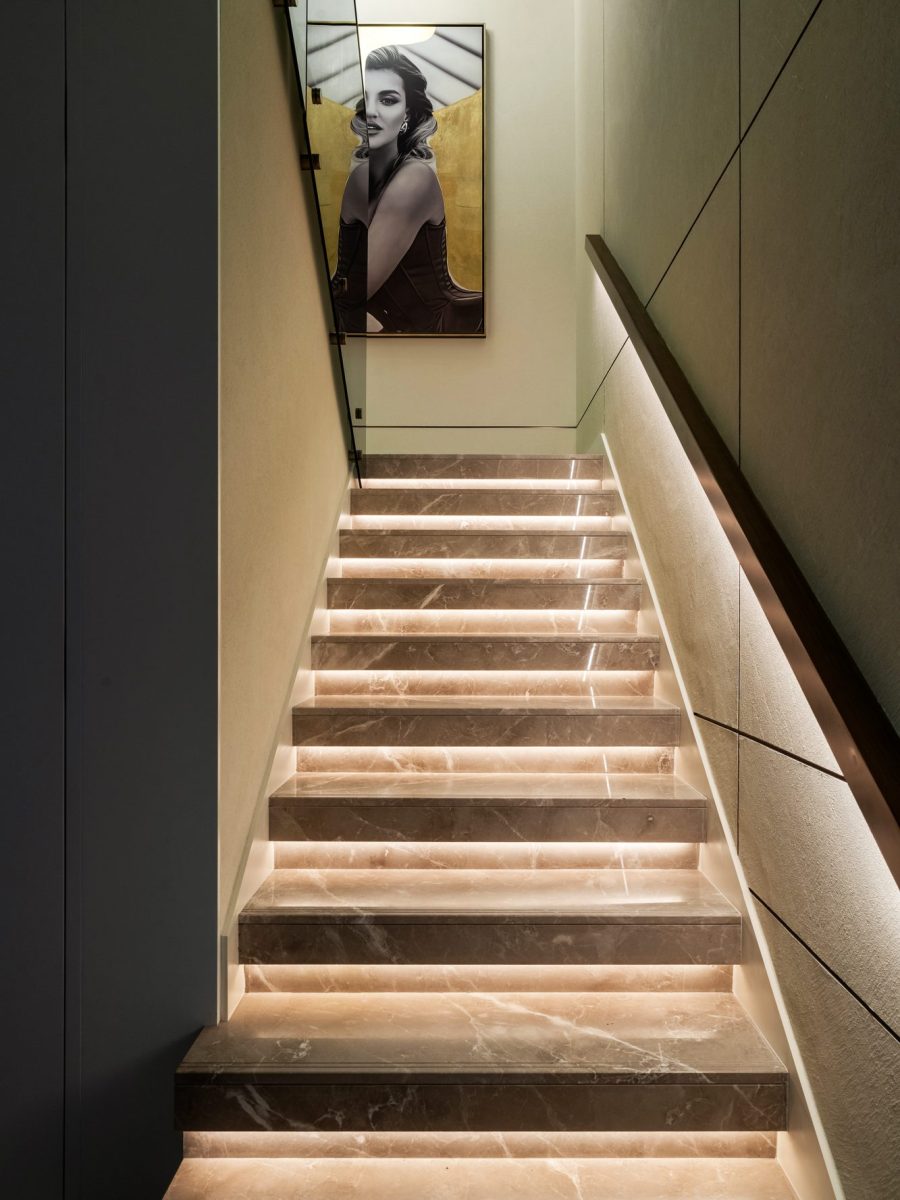 Staircase of the Peninsula townhouse with textured walls and lit steps